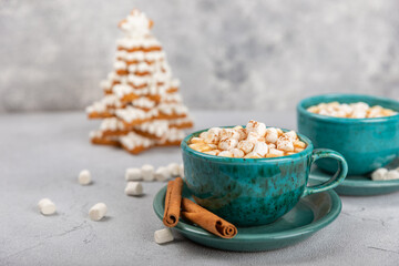 Hot drink with marshmallows and candy cane in cup on texture table.Cozy seasonal holidays.Hot cocoa...