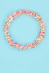 Easter wreath with mini eggs and apple blossom flowers. Abstract floral design for holiday season with mini eggs for card, logo, gift tag or invitation on pastel blue.