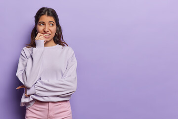 Horizontal shot of dark haired Iranian woman bites finger nails nervously clenches teeth looks...