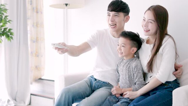 Relaxed Asian family watching TV together at home