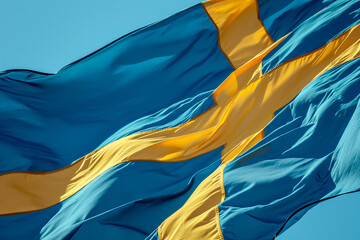 Swedish flag rippling in a vibrant blue sky.
