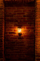 Burning lantern on a red brick wall