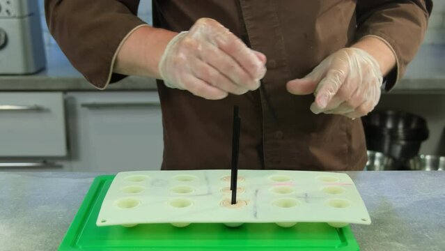 Creative male culinarian puts plastic straws in mold with pate. Restaurant chef about to serve meat balls in form of lollipop