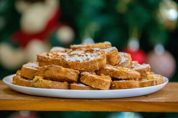 Typical Brazilian Christmas Rabanadas with egg yolk cream and cinnamon, Spanish Torrijas on golden plate on a Christmas dinner table. Fine details