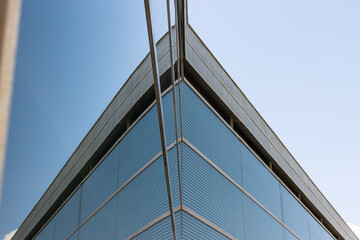Low angle view of the glass facade of a tall office building against a clear blue sky, - Powered by Adobe