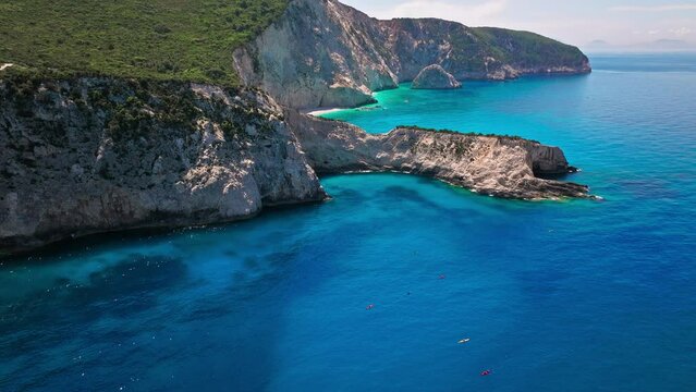 Kayaking Holidays on Porto Katsiki beach with turquoise water bordered by concave pale cliffs. Aerial view of tourists kayaking on crystal clear blue waters on the Ionian island of Lefkada, Greece.