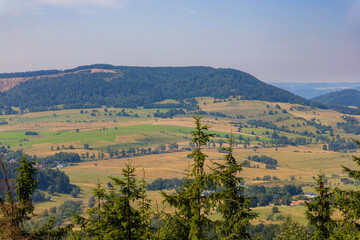 Beautiful green and blue panorama of layers of mountains and trees and some fields seen from top of viewing tower at highest mountain in this area