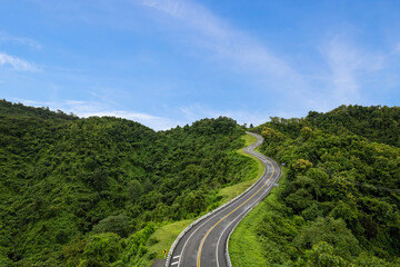 Fototapeta na wymiar Aerial view of countryside road passing through the green forest and mountain in Thailand.