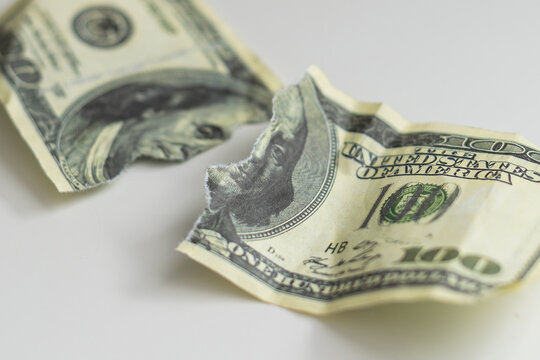 a one hundred dollar bill torn in half isolated on a white background