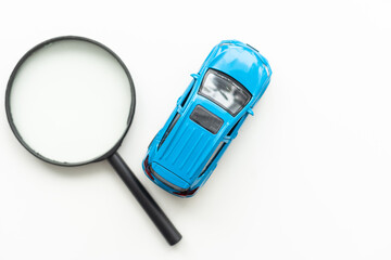 Toy car model and magnifying glass on white background
