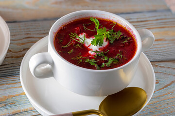 Ukrainian borscht (Beet Soup). Portion of Ukrainian borscht in tureen. Borsch served in white tureen with sour cream and parsley on wooden table
