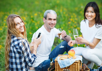 Happy smiling friends drinking champagne on picnic