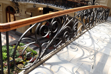 wrought iron railings enclose the bridge in a large store and cast a shadow on the floor