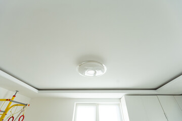 Round, minimalist, simple lamp on a white ceiling. A lamp that does not attract attention
