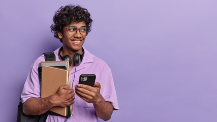 Student lifestyle. Indoor waist up of young happy smiling broadly Hindu guy wearing purple shirt...
