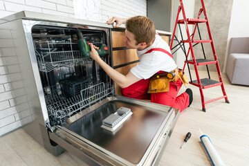 Concept maintenance service of home appliances. Worker cleans filter in the dishwasher. Male repairman checking food residue filters