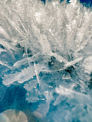Ice patterns in snowy mountains, village with houses, frosty day