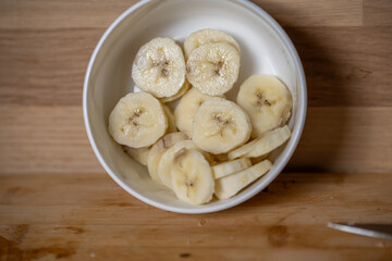tranches de bananes dans un ramequin blanc sur un plan de travail en bois
