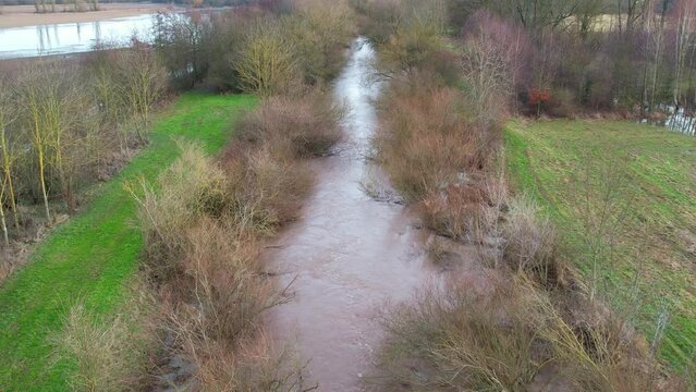 Hochwasser an einem Fluss mit &uuml;berfluteten Feldern