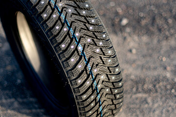 Studded winter tire stands on gravel.