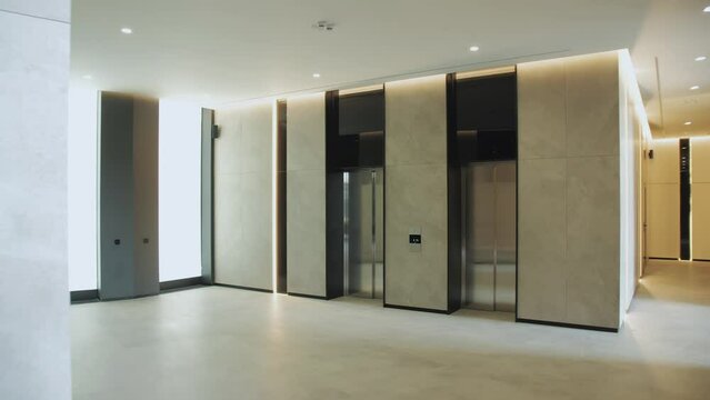 Spacious elevator hall in an apartment building, many small rounded lamps on ceiling illuminated hall, dolly shot, slow motion.