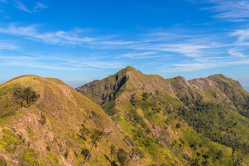 Green yellow mountains and beautiful sky clouds under the blue sky.