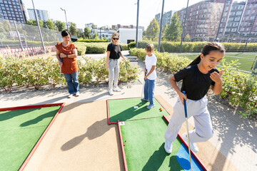 family playing mini golf on a cruise liner. Child having fun with active leisure on vacations.