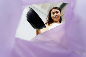 asian woman putting and sorting plastic food bowl waste to recycle bin POV. Low angle view from...