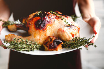 Woman holding plate with delicious roasted chicken