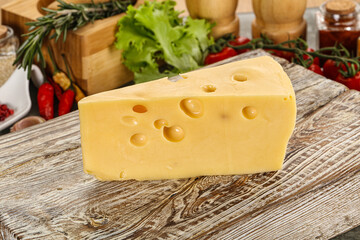 Swiss Maasdam cheese triangle over board