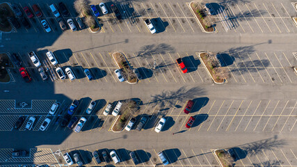 Top-down view of a parking lot with neatly aligned cars casting long shadows in the early morning...