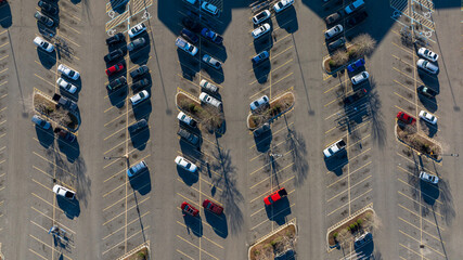 Top-down view of a parking lot with neatly aligned cars casting long shadows in the early morning...