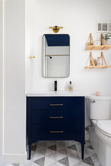 A bathroom with a dark blue cabinet and ceiling, a triangle pattern tile flooring, and decorations...