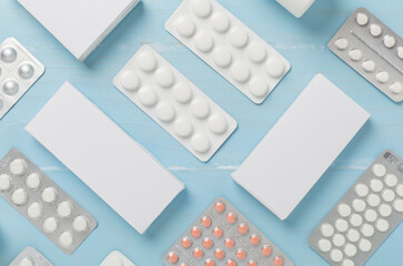 Different pills in blister packaging and boxes and on wooden background, top view