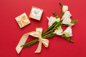 Fototapeta na wymiar White freesia flower and gift box with diamond ring on color background, top view