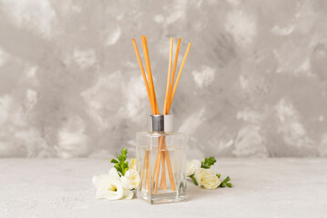 Reed aroma diffuser with freesia flower on concrete background