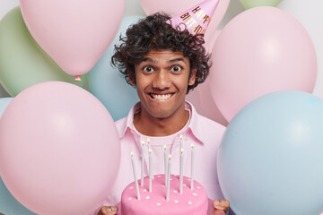 Photo of positive Hindu man with curly hair expresses pure joy and delight at birthday celebration...
