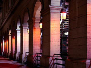 Colonnes illuminées en couleur d'un monument d'architecture ancien dans le centre ville historique. Arcades de circulatiion avec lanternes vintages de nuit.
