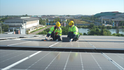 Both of technicians is installing solar panels on the roof of the warehouse to change solar energy into electrical energy for use in factories.