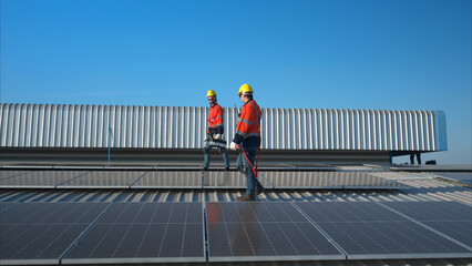 Both of technicians is installing solar panels on the roof of the warehouse to change solar energy into electrical energy for use in factories.