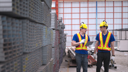Warehouse workers in hard hats and helmets, Inspect and count steel in the warehouse.
