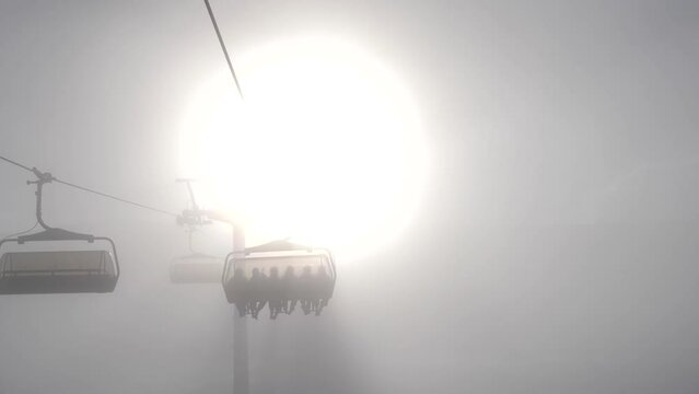 ski chairlift going up trough sun