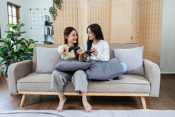 Young woman lesbian couple sitting on the comfortable sofa and playing game console while spending...