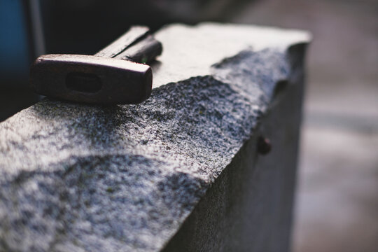 old hammer with broken handle on granite stone