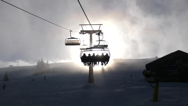 ski chairlift in ski resort going up with big sun.