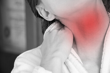 A girl holds her hands behind her neck at home in a dressing gown, her neck hurts, acute pain