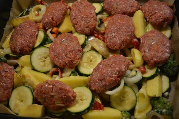 Healthy, wholesome, high-quality food, fresh chopped vegetables and cutlets placed on a large metal baking sheet.