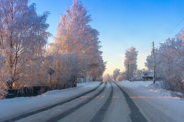 Winter landscape. Snowy road in a village on a frosty clear day