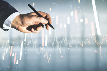 Multi exposure of businessman hand with pen working with virtual creative financial graph and world map on blurred office background, forex and investment concept