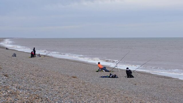 Sea anglers beach fishing from the Stony bank at Weybourne beach on the North Norfolk coast